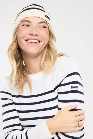 Woman wearing a navy striped sweater and matching beanie, smiling, casual winter fashion
