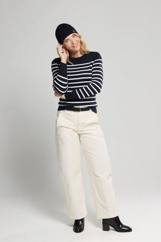 Woman in navy striped sweater, beige wide-leg pants, navy beanie, and black boots