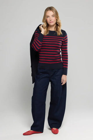 Woman wearing a navy and red striped sweater with wide-leg dark jeans and red flats