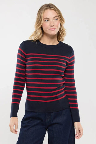 Woman wearing a navy blue sweater with red horizontal stripes and dark pants