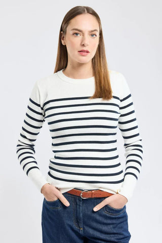 Woman wearing a navy and white striped sweater with blue jeans, hands in pockets