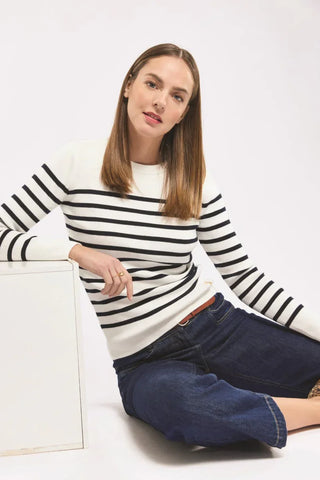 Woman in a white and navy striped sweater and blue jeans sitting on the floor