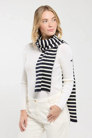 Woman wearing navy and white striped scarf with white sweater, stylish winter fashion