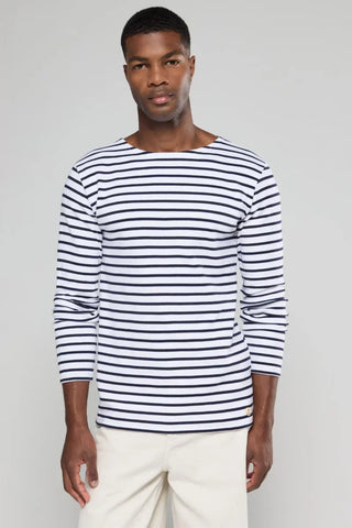 Man wearing a long sleeve white and navy striped Breton shirt with cream pants