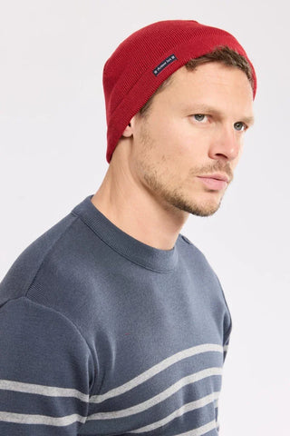 Man wearing a red knit beanie and blue striped sweater, casual winter fashion.