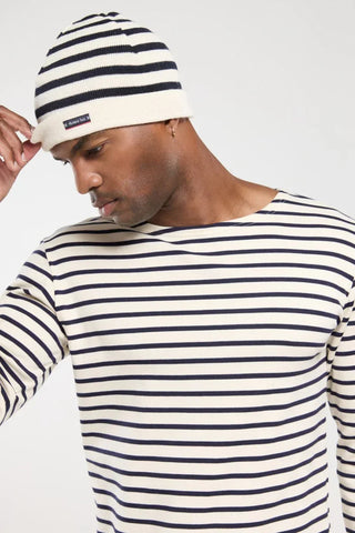 Man wearing navy and white striped beanie and long-sleeve shirt, nautical style fashion.
