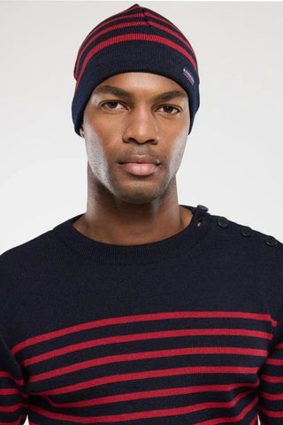 Man wearing navy blue and red striped knit beanie and matching striped sweater