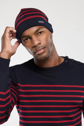 Man wearing navy blue and red striped knit beanie and matching striped sweater