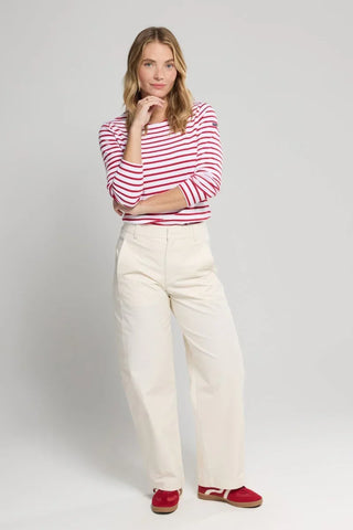 Woman wearing red and white striped long sleeve shirt, cream wide-leg pants, red sneakers