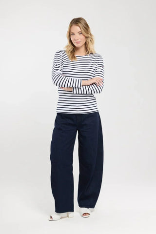 Woman wearing navy striped long sleeve top with wide leg dark jeans and white heels