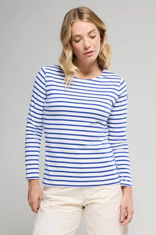 Woman wearing a white and blue striped long-sleeve shirt with ivory pants