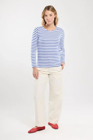 Woman wearing blue and white striped long-sleeve top, cream pants, and red flats