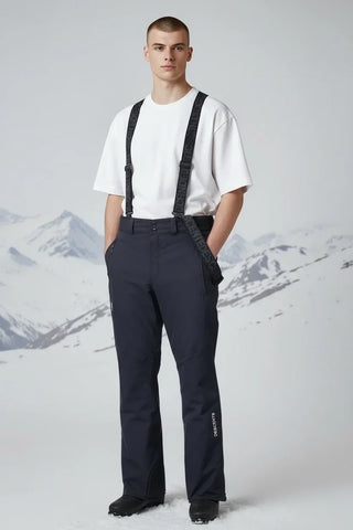 Man wearing black ski pants with suspenders and a white t-shirt, standing in snowy mountains