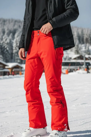 Man wearing bright red ski pants and white ski boots on a snowy mountain slope