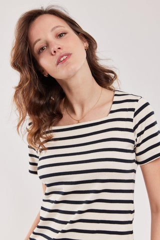 Woman wearing a short sleeve navy and white striped cotton top, neutral background