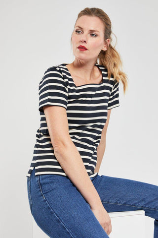 Woman in a black and white striped short-sleeve cotton top and blue jeans sitting