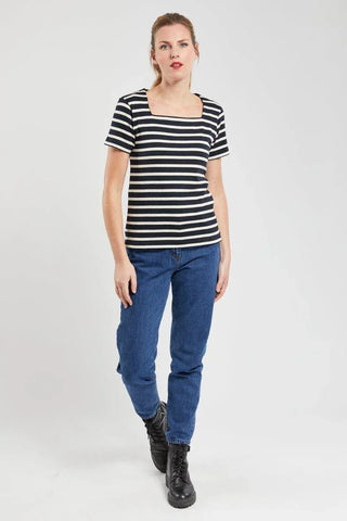 Woman wearing short-sleeve navy striped cotton marinière top, blue jeans, and black boots