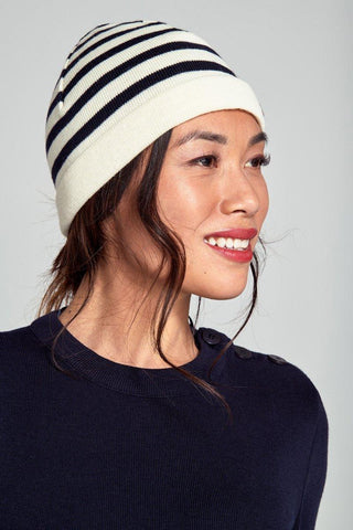 Woman wearing navy and white striped wool beanie and navy sweater, side profile
