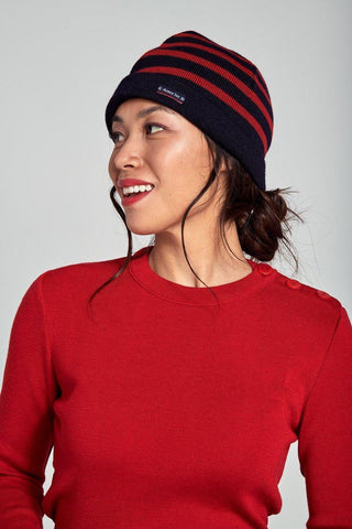Woman in a red sweater wearing a navy and red striped knit beanie, side view