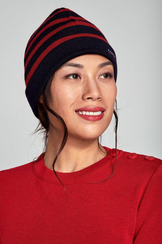 Woman wearing a navy and red striped wool beanie and red knit sweater