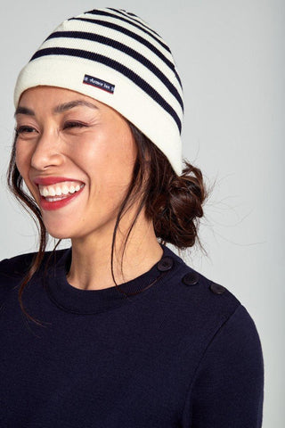 Smiling woman wearing a white and navy striped knit beanie and navy sweater