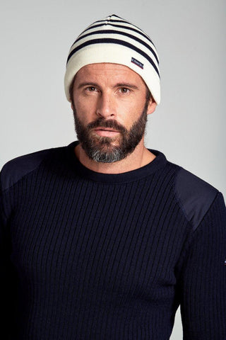 Man wearing a navy ribbed sweater and white knit beanie with navy stripes