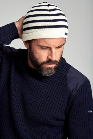 Man wearing a navy and white striped knit beanie and a navy ribbed sweater