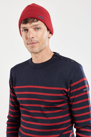 Man wearing a red wool beanie and navy blue with red striped Breton sweater