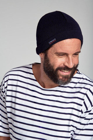 Man wearing navy blue knit beanie and white striped Breton shirt, smiling