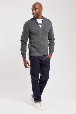 Man wearing a grey zip wool cardigan, striped shirt, dark jeans, and white sneakers