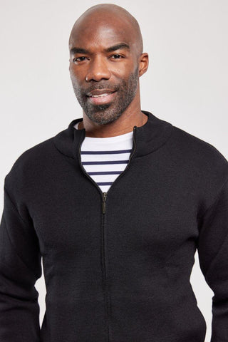 Man wearing black zip wool cardigan over striped shirt, close up, neutral background