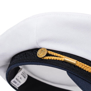 Close-up of a white sailor captain hat with gold rope and anchor button detail