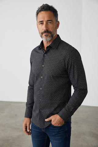 A man wearing a black Bugatchi James long-sleeve shirt with a wine glass print, made from stretch OoohCotton fabric.