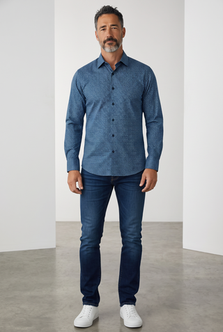 A model wearing a navy blue Bugatchi James long-sleeve shirt with a diamond pattern, paired with jeans and white sneakers.