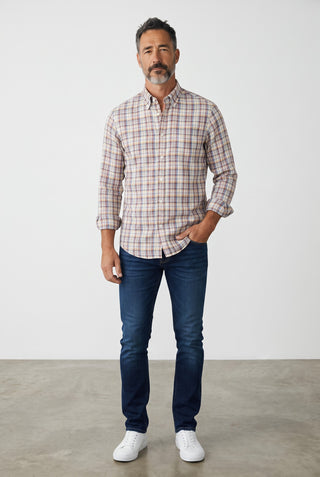 Homme portant une chemise à carreaux en flanelle Le Capitaine D'a Bord avec un jean bleu et des baskets blanches