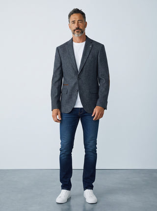 Homme portant un veston en laine gris Le Capitaine D'a Bord avec coudières, t-shirt blanc et jean bleu