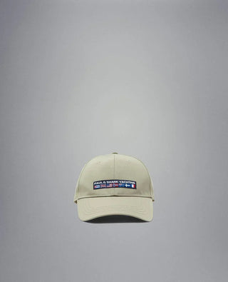 Beige nylon yachting cap with embroidered flags and logo patch on front, isolated on grey.