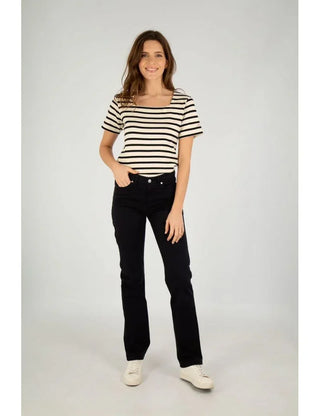Woman wearing short-sleeve striped cotton mariniere shirt and black pants, standing, studio background