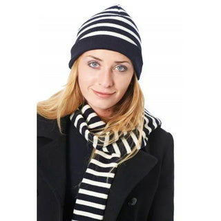 Woman wearing navy and white striped knit beanie and scarf with black coat