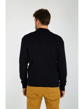 Man wearing a dark wool cardigan and mustard pants, shown from the back.