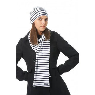 Woman wearing a black coat with matching white and navy striped cotton beanie and scarf