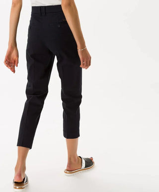 Woman wearing navy cotton satin capri pants, back view, cropped length, white sandals