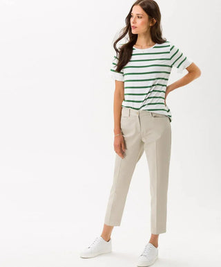 Woman wearing beige cotton capri pants and striped green and white t-shirt, white sneakers