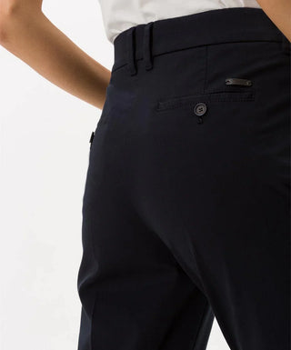 Back view of navy blue cotton capri pants with buttoned pocket, worn by a woman