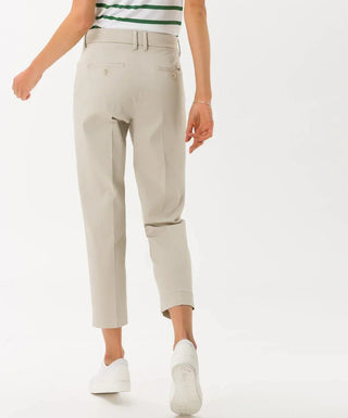 Woman wearing beige cotton satin capri pants, white sneakers, green striped top
