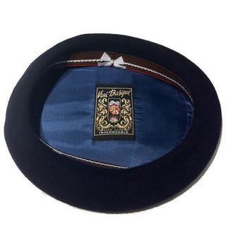 Interior view of classic Basque beret with navy lining, embroidered crest, and bow detail