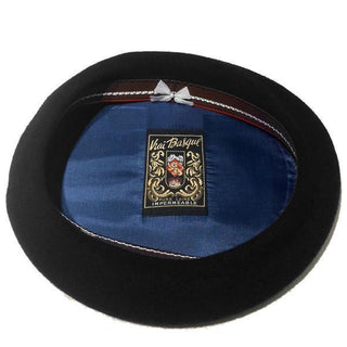 Interior view of a black Basque beret with blue lining and decorative label