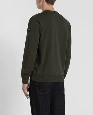 Man wearing dark green crew neck sweater with shoulder patches and dark jeans, back view