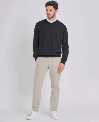 Man wearing black V-neck merino wool sweater, beige pants, and white sneakers
