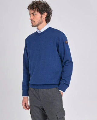 Man wearing blue merino wool V-neck sweater and grey pants, fashion menswear style